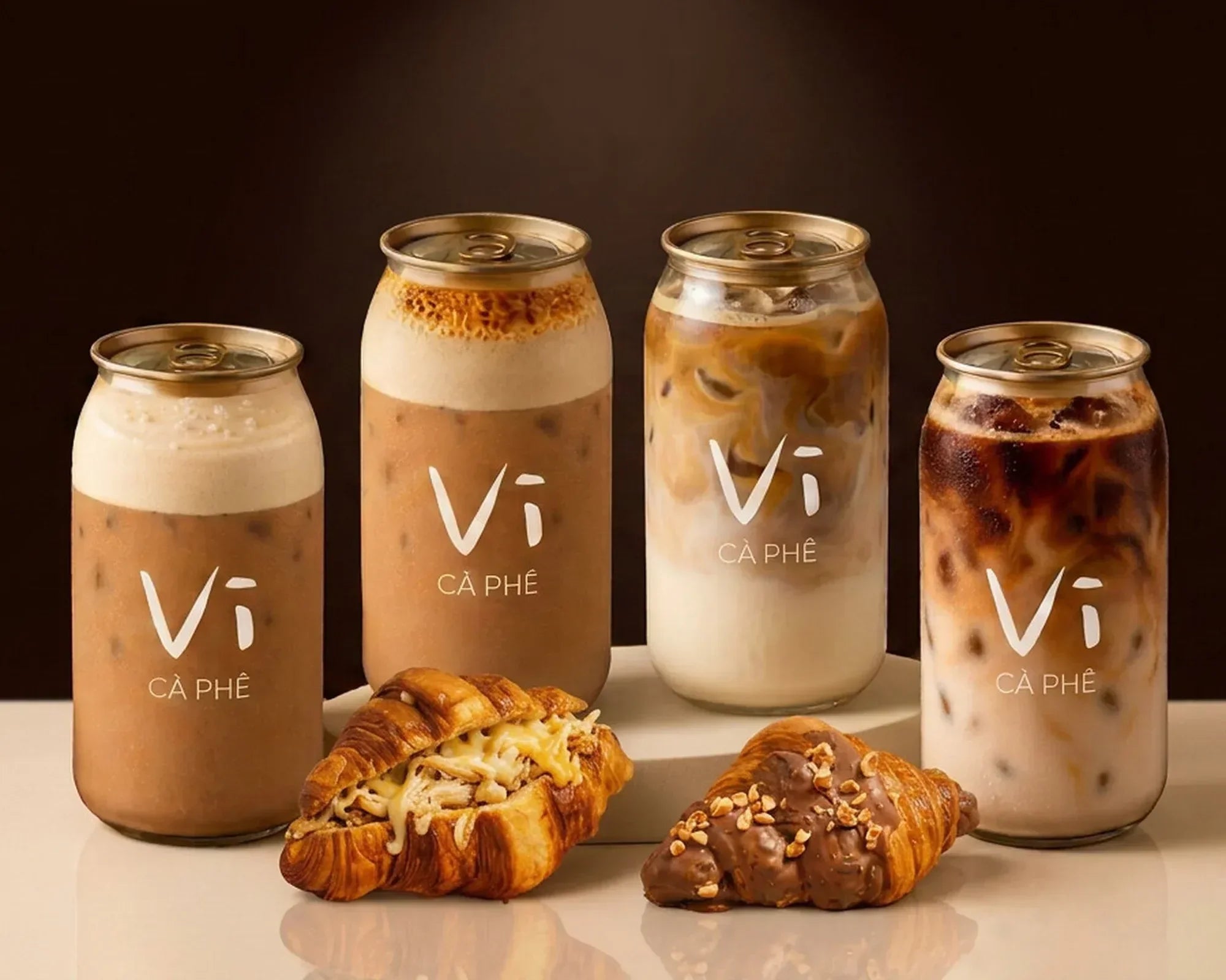 An ube yoghurt can, an egg coffee can on a terracotta plinth and a pistachio croissant
